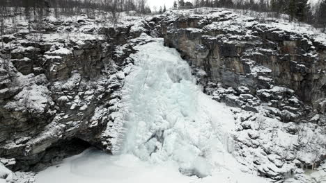 frozen waterfall down cliffs in snowy winter landscape