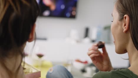 Rückansicht-Von-Freunden,-Die-Schokolade-Essen,-Während-Sie-Auf-Dem-Sofa-Sitzen