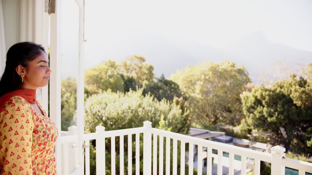 Standing on balcony, woman enjoying scenic view of lush green landscape, copy space