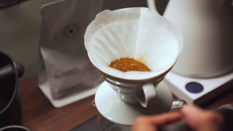 barista vierte café molido fresco en goteo de cerámica con filtro de papel
