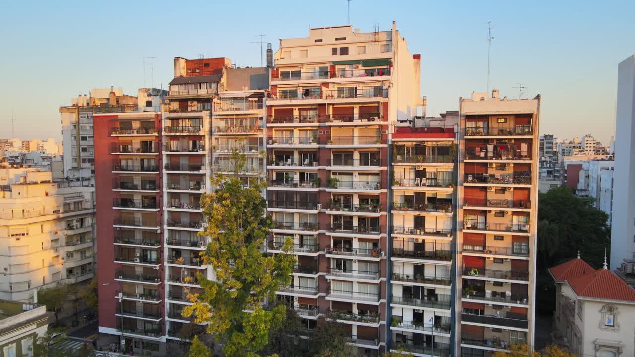 Residential mid rise apartment building with balconies and sunset lighting near Parque Rivadavia in Buenos Aires. Drone dolly in movement.