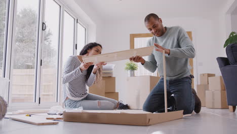 couple in new home on moving day putting together self assembly furniture