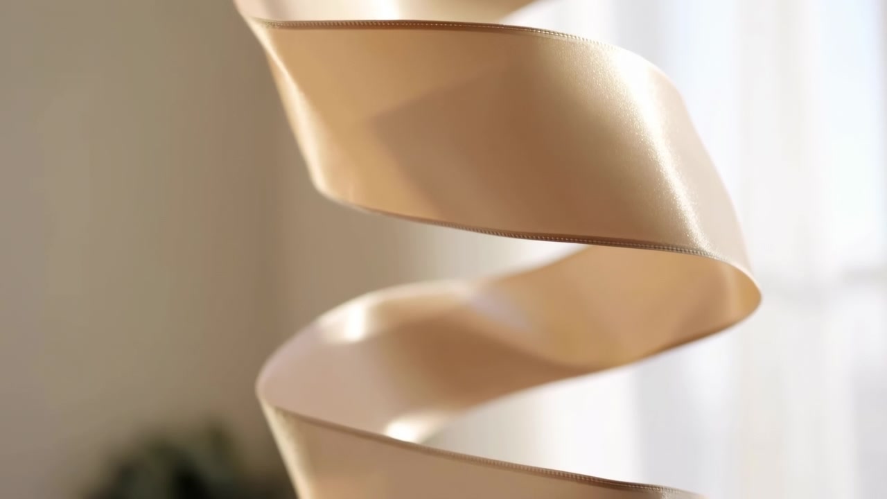Un nastro di raso beige astratto che scorre verticalmente su uno sfondo neutro sfocato, con una luminosa illuminazione laterale che ne evidenzia la texture liscia e delicata