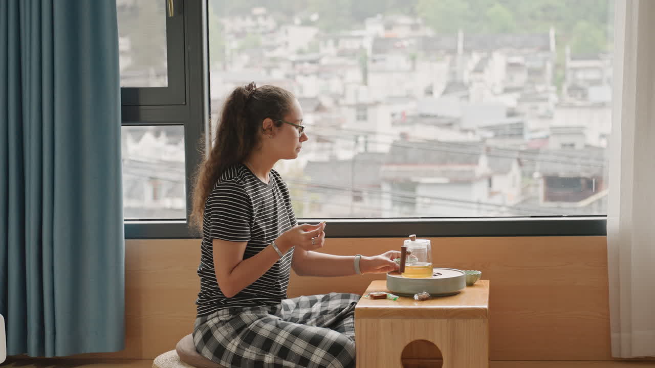 Una donna fa colazione. Una visitatrice è seduta accanto alla finestra, godendosi un'abbondante colazione mattutina con vista panoramica. La donna si rilassa e apprezza la sua colazione ammirando lo splendido paesaggio urbano dalla finestra dell'hotel.