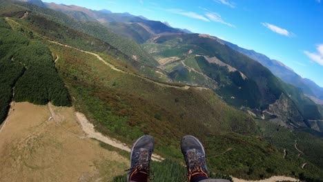 pov paragliding over tasman richmond ranges with forest, hills and dramatic terrain, hiker shoes and long pants as feet kick with joy