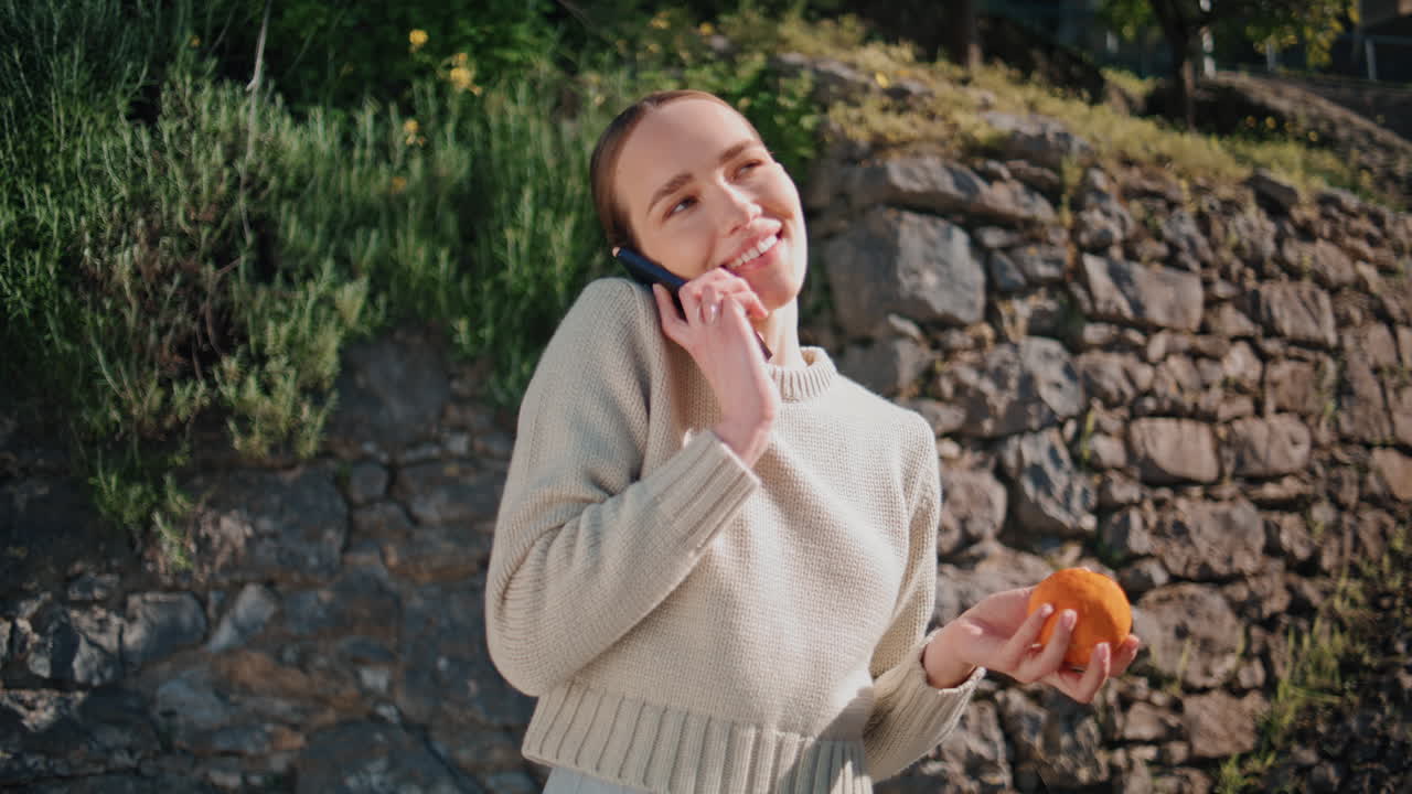 Carefree woman playing orange at sunny park closeup. Happy girl answering call