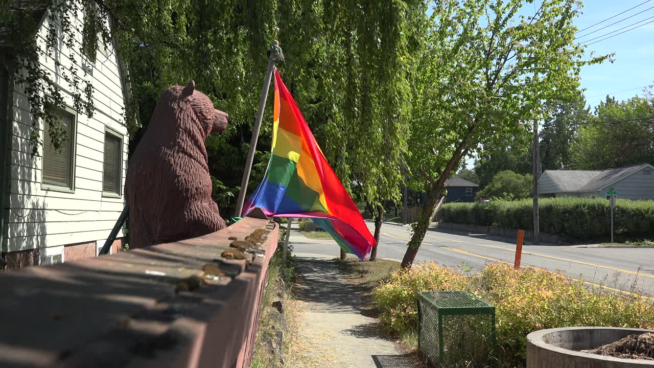LGBTQ flag blowing in the wind at sunny street.