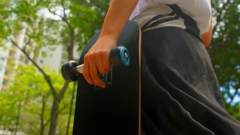 sección media de una mujer con patineta caminando por la calle 4k