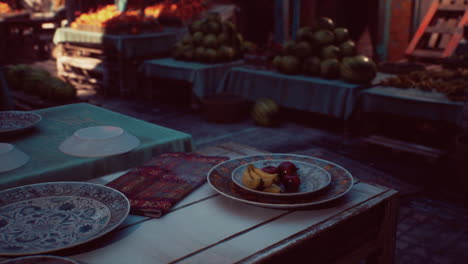 un vibrante mercado al aire libre con frutas y productos frescos en exhibición. platos de colores y un mantel de mesa con patrones añaden a la escena.