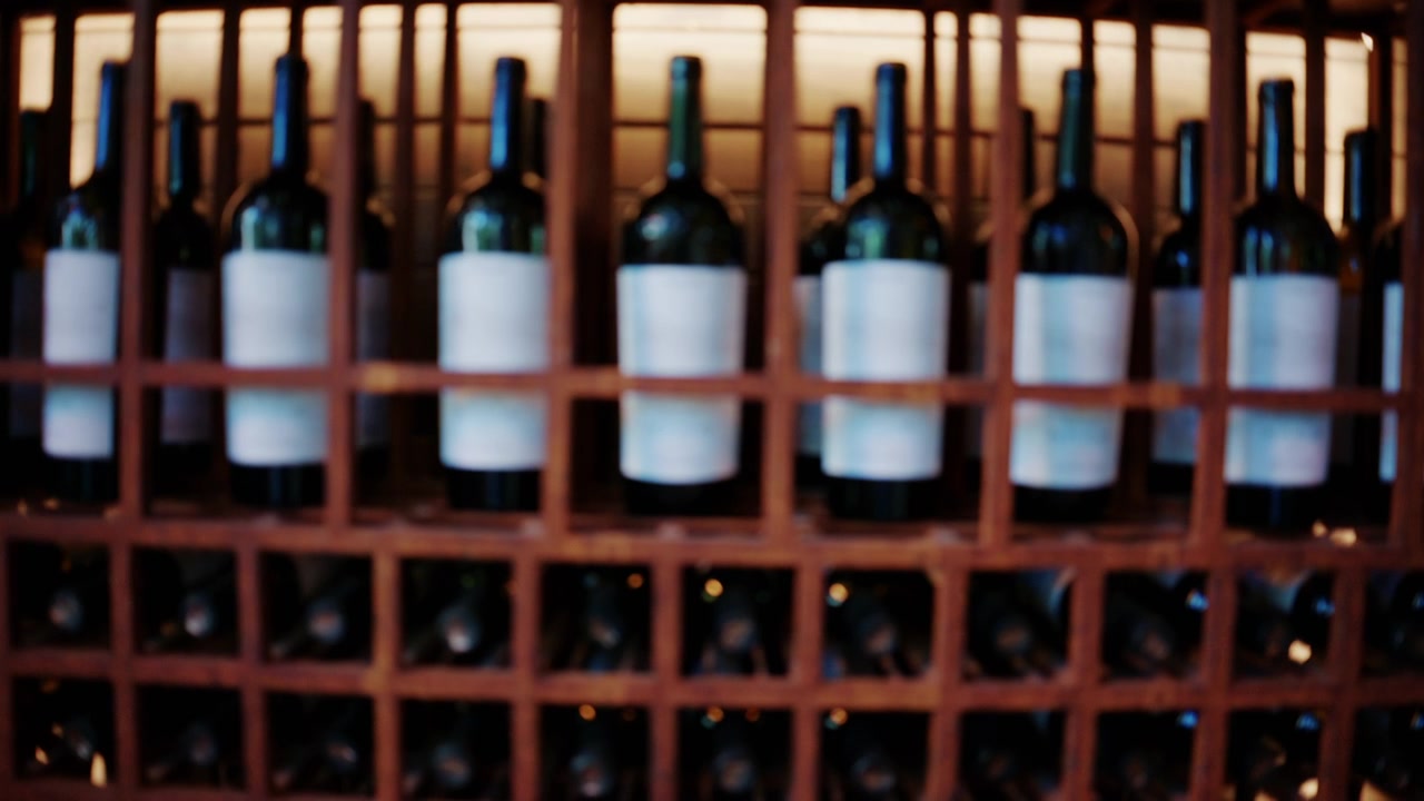 File di bottiglie di vino conservate in una scaffalatura in legno per cantina.