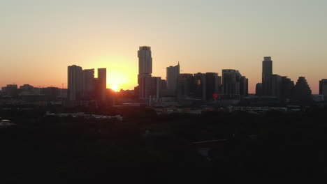 aerial telephoto tracking shot of downtown austin, texas skyline at dawn on a summer day