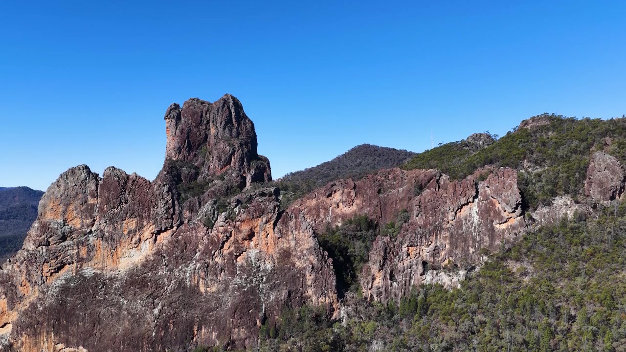 Vidvinkelbillede af gamle vulkanske tinder og klipper under en klar blå himmel i Australien