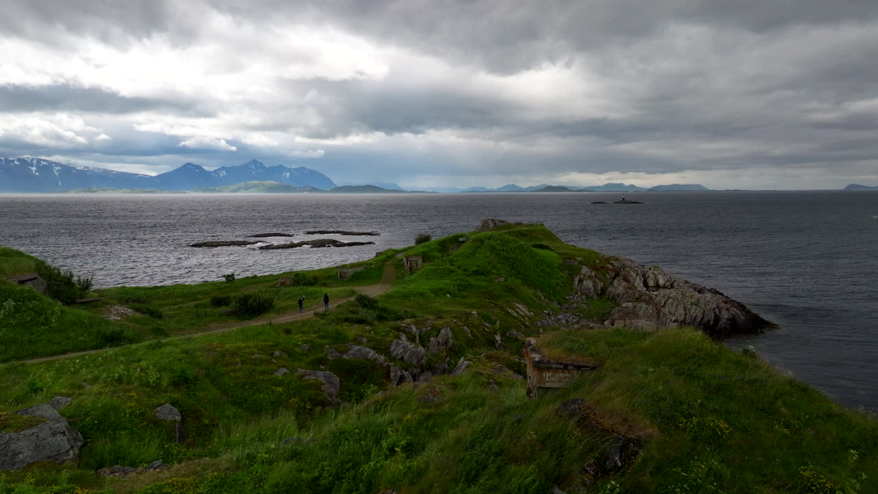 Ruins at Skrollsvik Fort on Senja island, old gun emplacement on dramatic coastline with mountains in background. Norway. Aerial forward