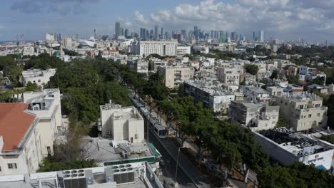 Light-rail-driving-through-suburban-residential-streets-with-city-skyline-in-the-background