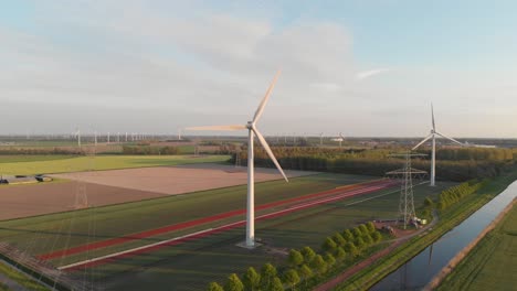 scenic view of wind turbines and electricity towers with small river stream in flevoland, netherlands