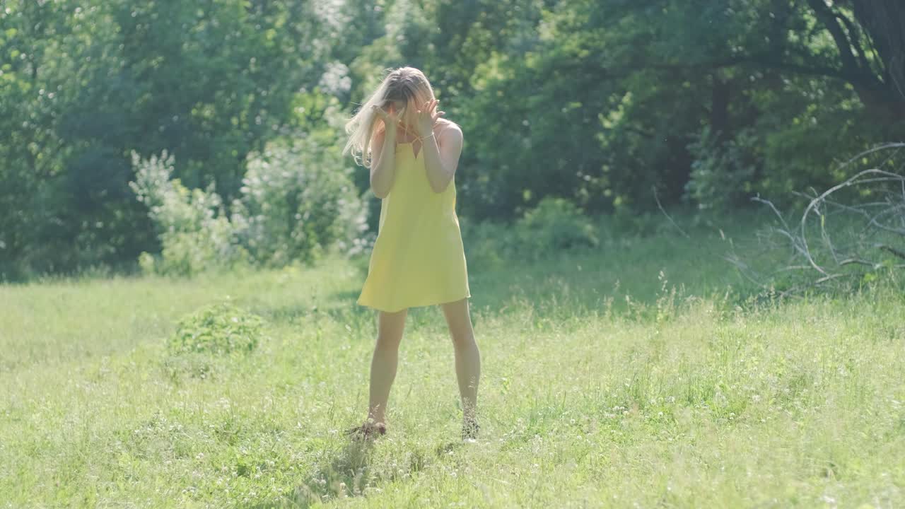 노란색 드레스를 입은 여자가 여름 공원에서 우아하게 춤을 춘다