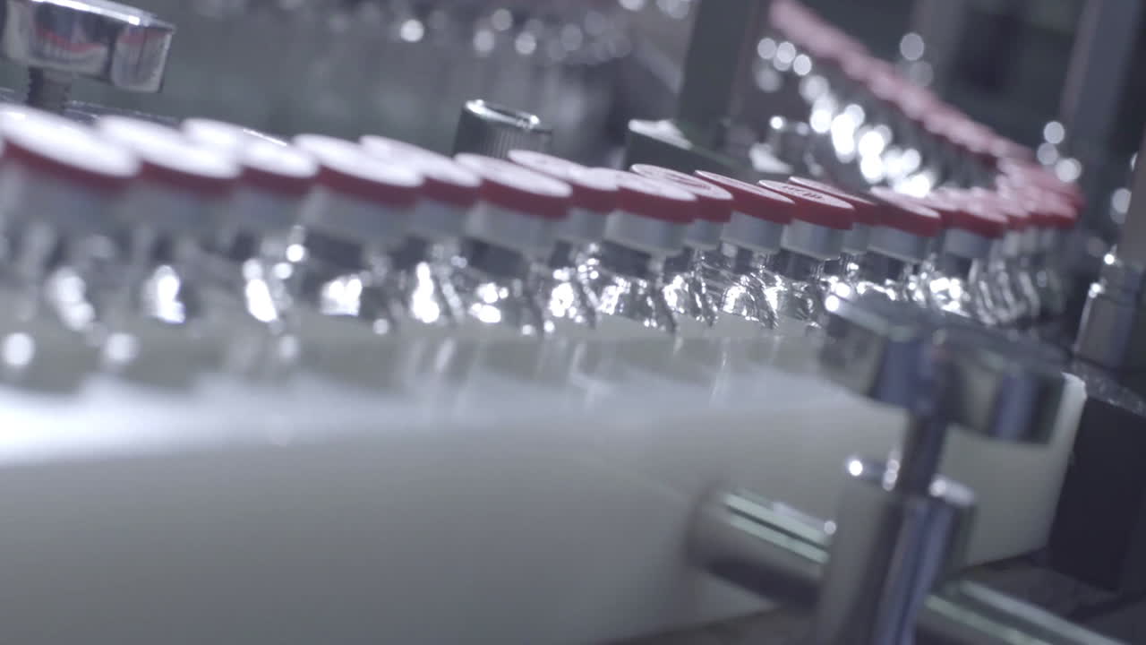 una gran cantidad de frascos de vidrio vacíos frascos con tapas rosas para drogas se mueven a lo largo de la línea de procesamiento en una fábrica