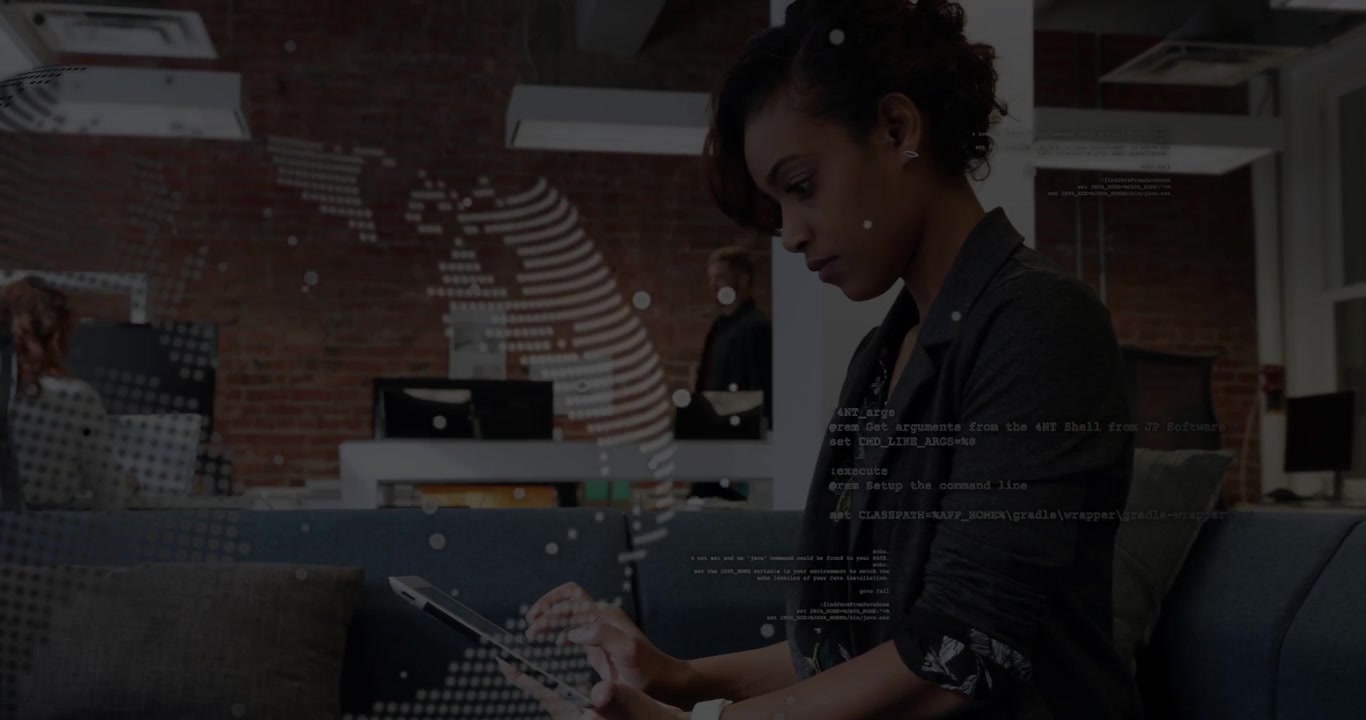 Vertical video: Woman tapping tablet starting globe overlay pulling back showing team working in IT