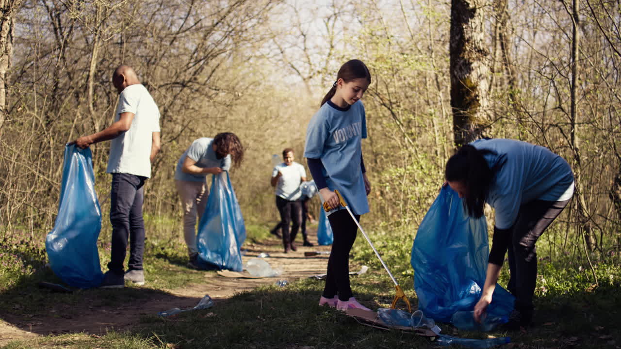 madre y niño recogiendo basura de la zona del bosque usando una herramienta de garras largas