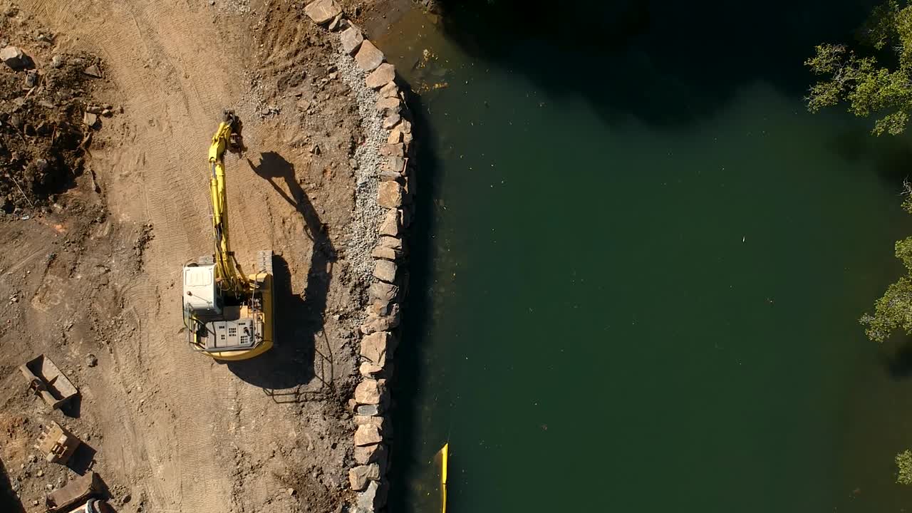 una gran excavadora reparando una sección del río dañada por una inundación causada por un ciclón tropical.