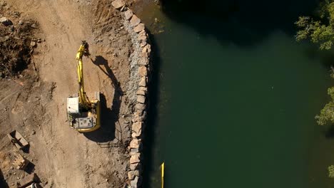 a large excavator repairing a section of river damaged by a flood waters caused by a tropical cyclone