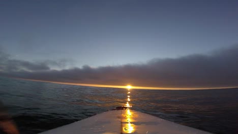 surfista viendo una enorme puesta de sol en el cielo nublado sobre el mar