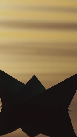 paper boat by handmade is floating on the waves of the river at sunset. the image of a paper ship is reflecting in the water in the evening. vertical video