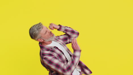 mature man strums playing on invisible imaginary guitar energetically dancing rocknroll music
