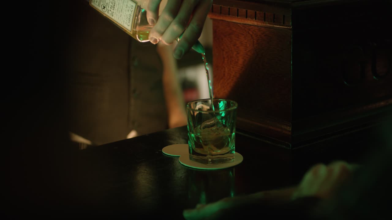 Bartender preparing drink for man at counter. Handheld. Shallow focus