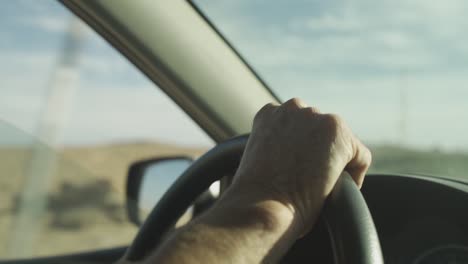 cu de la mano del hombre en el volante en el desierto