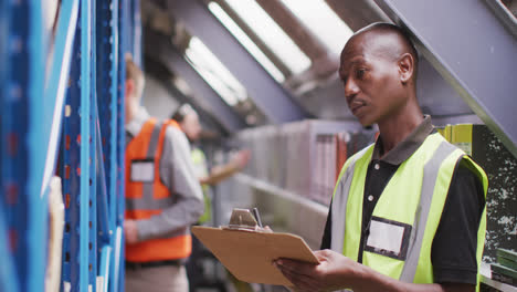 un trabajador de fábrica afroamericano en una fábrica que hace equipos hidráulicos tomando notas