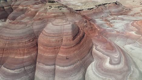 aerial view, person walking down on layered sandstone hill in utah desert, mars look alike landscape, drone shot