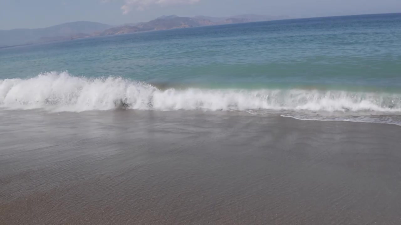 Onde dell'oceano che si infrangono dolcemente sulla riva di una spiaggia sabbiosa