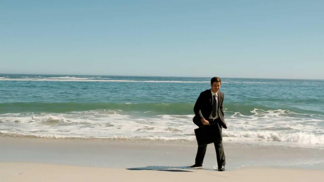 행복한 사업가 가방을 해변에 던지고