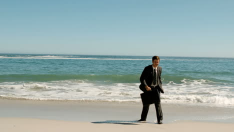 Happy-businessman-throwing-his-suitcase-on-the-beach