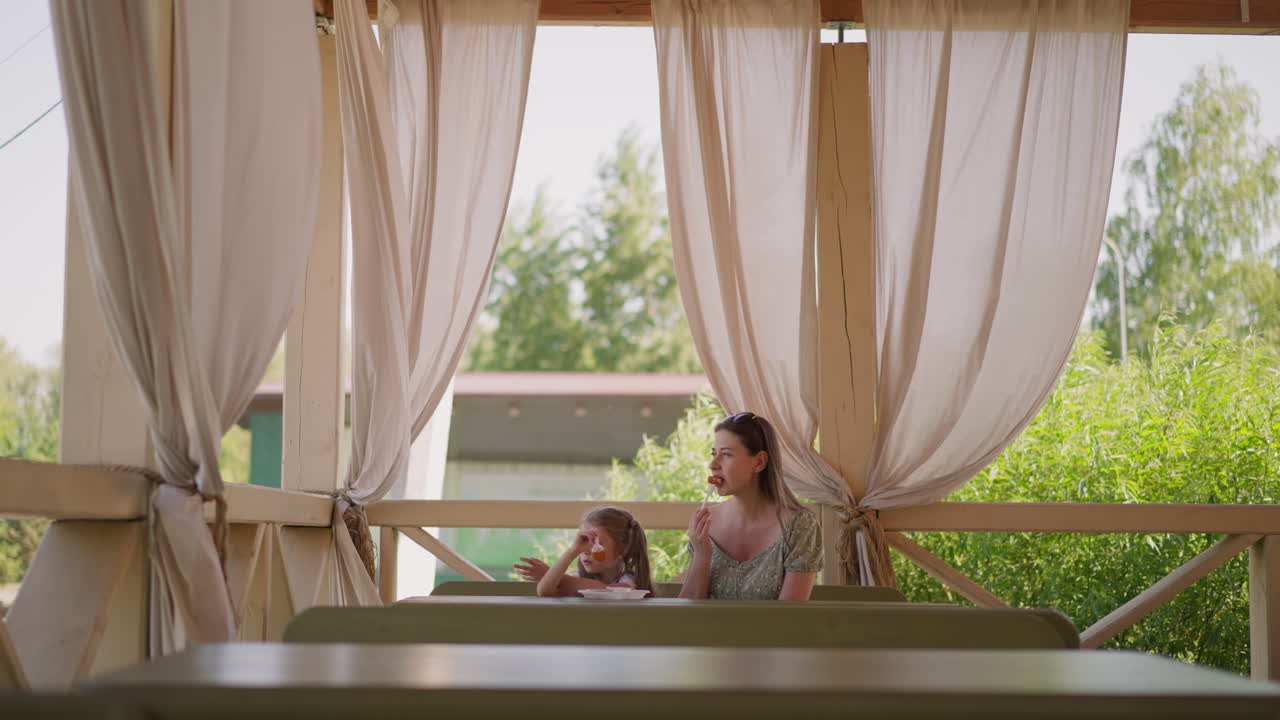 mujer con hija disfruta de frituras de cuajada en la terraza del café