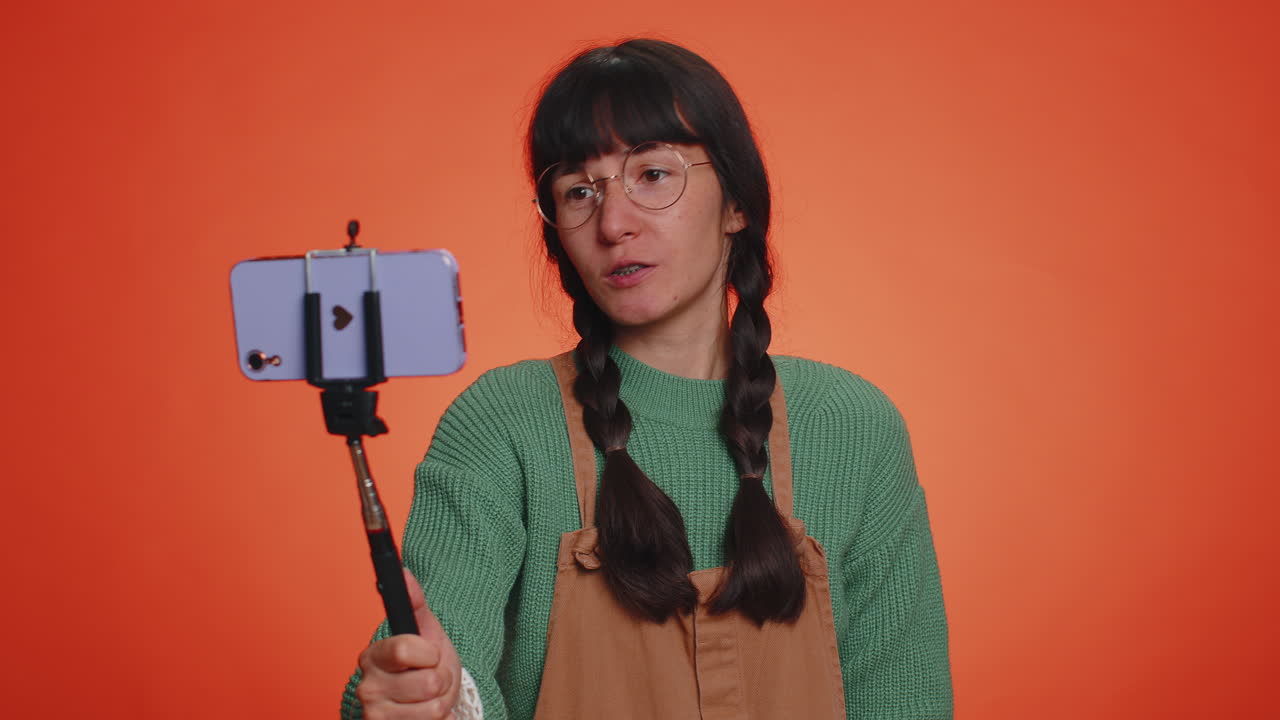 여성 여행자 블로거가 휴대 전화로 셀피를 찍고, 온라인 구독자를 통해 비디오 통화를 통신합니다.