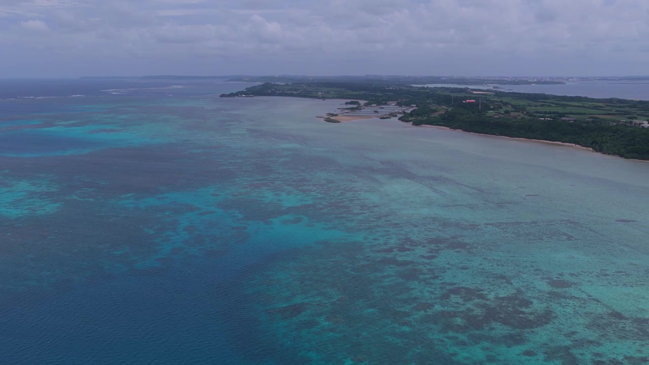 Inquadratura orizzontale con panoramica verso destra sopra la barriera corallina turchese e l'oceano aperto che circonda l'isola di Ikema, Miyakojima, Okinawa, Giappone