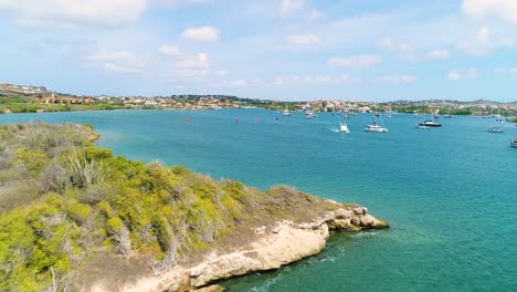 aerial dolly above rocky coastline in curacao to spanish waters harbor