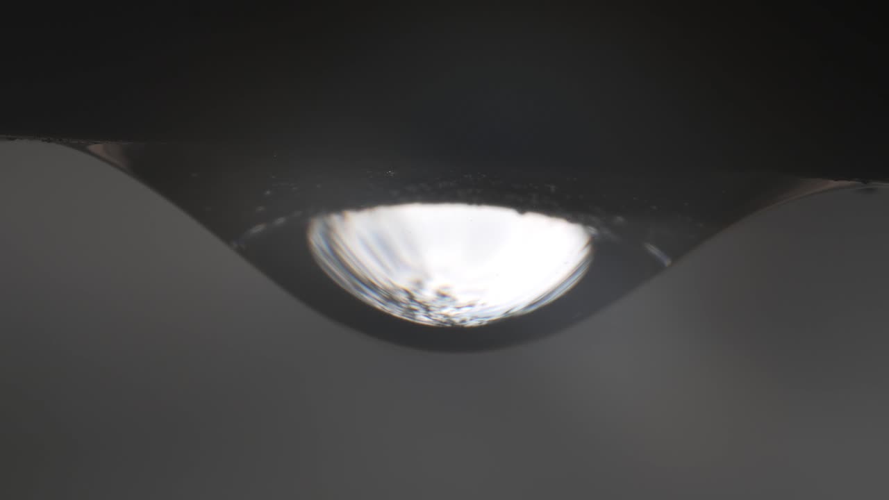 primer plano extremo de gotas de agua de lluvia, partículas que se mueven dentro de la superficie brillante