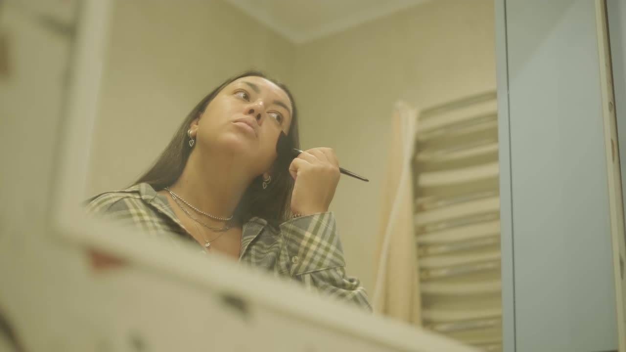 una mujer embarazada de pie cerca de un espejo en casa, vistiéndose. la escena refleja el cuidado de sí misma, la maternidad y la vida cotidiana en un entorno cálido y personal