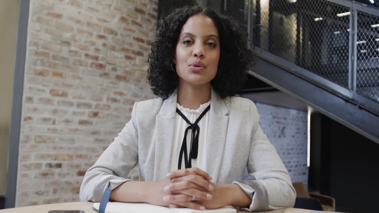 feliz mujer de negocios casual biracial haciendo una videollamada en el salón de la oficina, cámara lenta