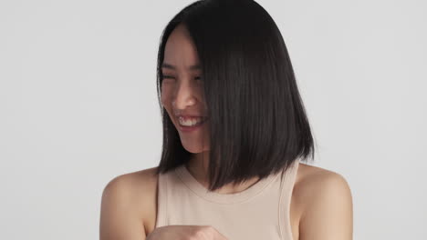 asian woman looking shy on camera.