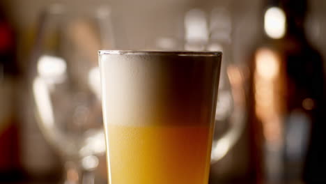 craft beer being poured in to a pint glass, light background, close up