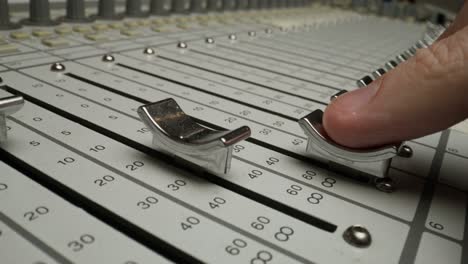 hand adjusting faders on an audio mixer