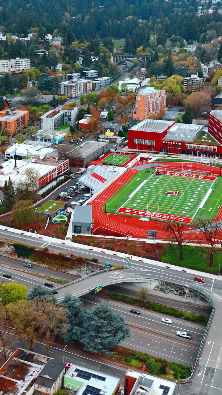 Vivace autostrada a più corsie con ponti sopra. Stadio verde di una scuola nello scenario di Portland, Oregon, USA. Molto verde sullo sfondo. Video verticale