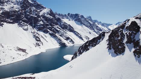 lago escénico rodeado de montañas rocosas nevadas en la estación de esquí de portillo, montañas de los andes de chile