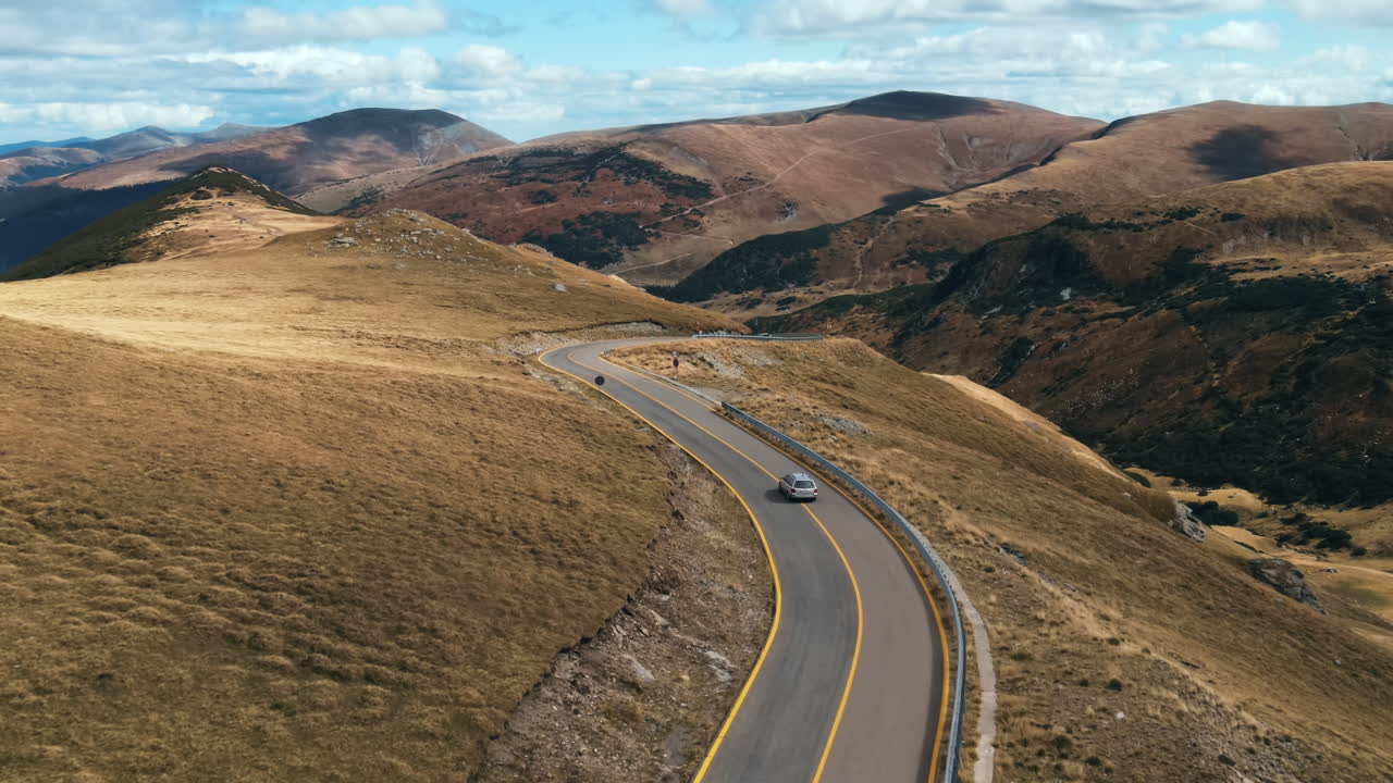 Aerial drone view of nature in Romania. Carpathian mountains, sparse vegetation, Transalpina road with cars