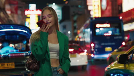 woman talking on phone in a busy city street at night