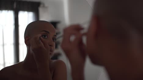 serious black woman doing makeup at home